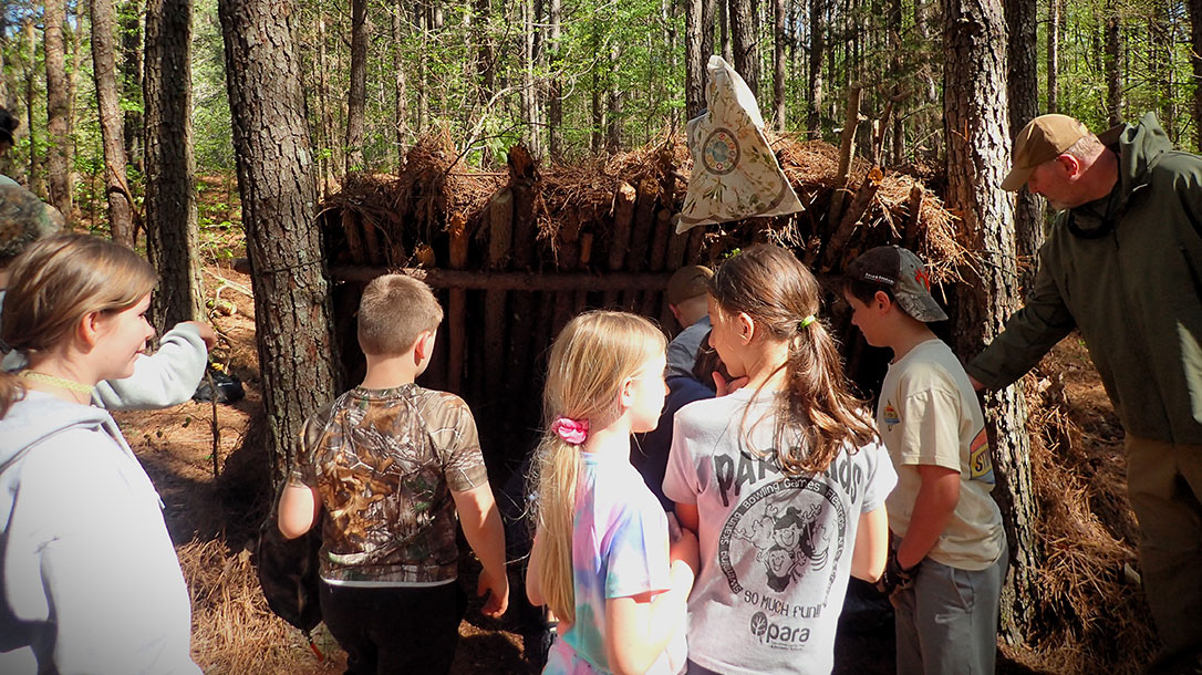 Teaching Kids Wilderness Survival: Building a lean-to shelter should be a group event where everyone helps accomplish a set goal.